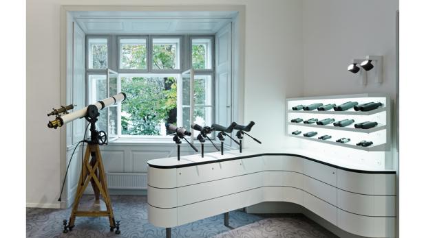 Ein Ausstellungsraum mit Teleskopen und Ferngläsern vor einem Fenster.