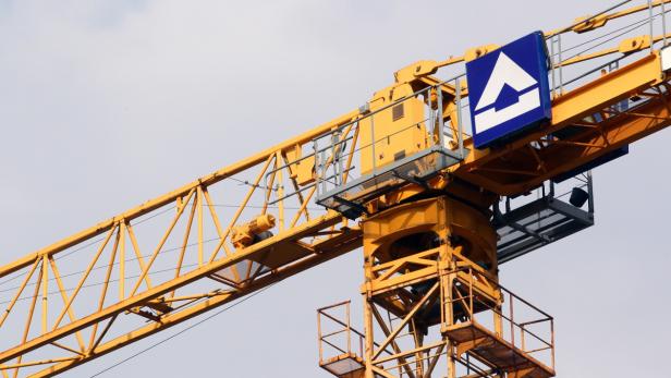 Nahaufnahme eines gelben Baukrans vor einem hellen Himmel.