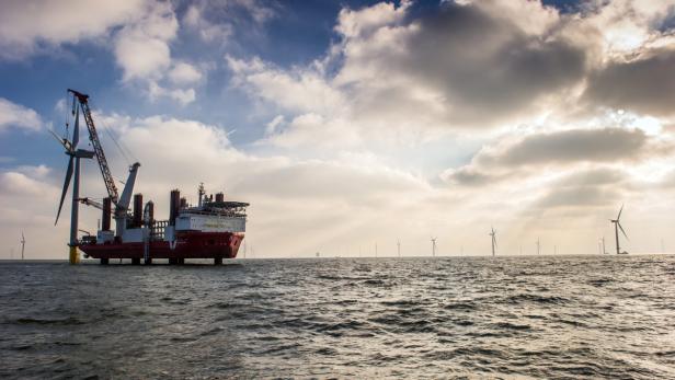 Ein Schiff installiert eine Windkraftanlage in einem Windpark auf See.