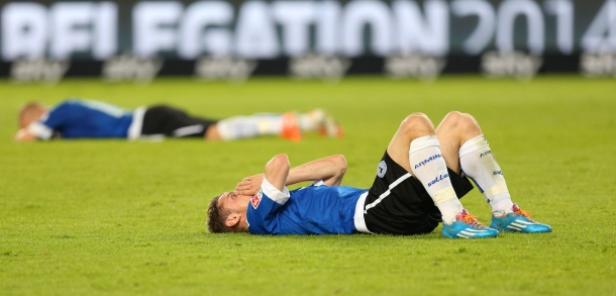 Ein enttäuschter Fußballspieler liegt auf dem Rasen und hält sich das Gesicht.