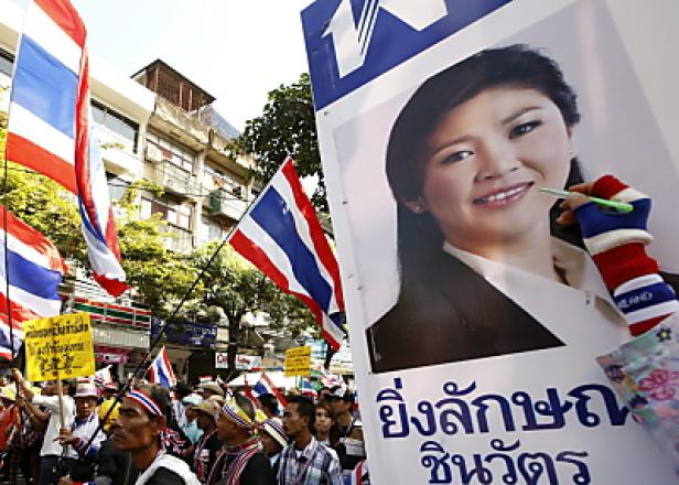 Demonstranten in Thailand mit thailändischen Flaggen und einem Plakat von Yingluck Shinawatra.