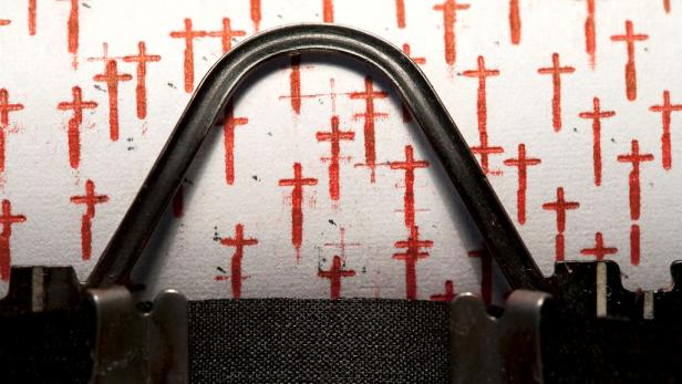 Nahaufnahme einer Schreibmaschine, die rote Kreuze auf ein Blatt Papier tippt.