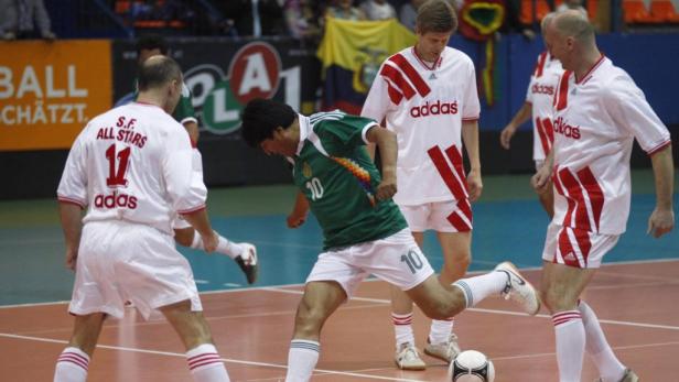 Ein Fußballspieler im grünen Trikot schießt den Ball während eines Hallenfußballspiels.