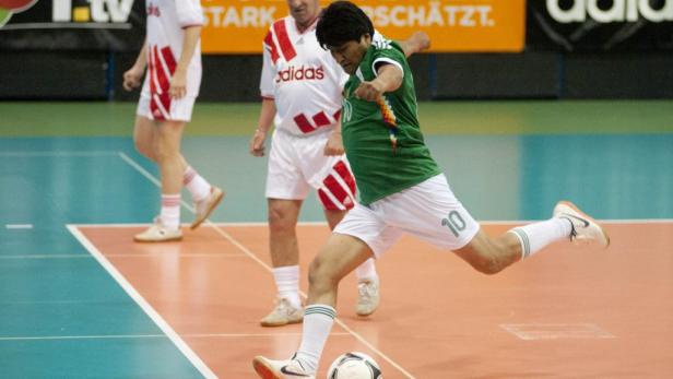 Ein Mann in Sportkleidung schießt einen Fußball.