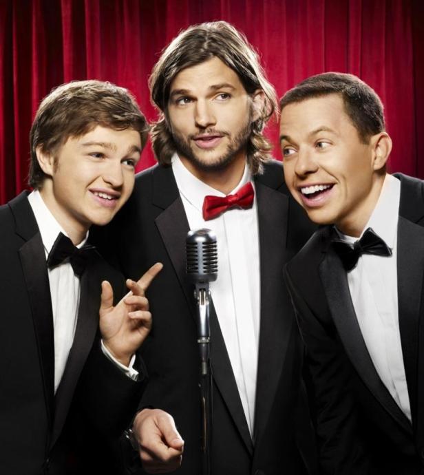 Die Schauspieler Angus T. Jones, Ashton Kutcher und Jon Cryer posieren in Anzügen vor einem Mikrofon.