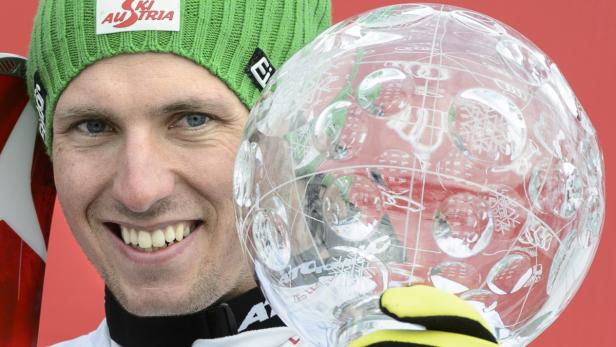 Ein Skirennläufer mit einer großen Kristallkugel in der Hand.