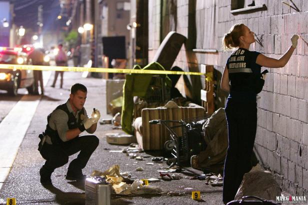 Zwei Kriminaltechniker untersuchen einen Tatort in einer Gasse bei Nacht.