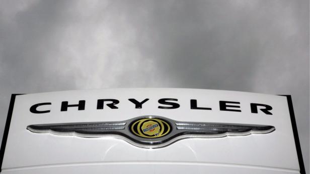 Das Chrysler-Logo auf einem weißen Fahrzeug vor einem bewölkten Himmel.
