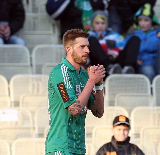 Ein Fußballspieler in grüner Spielkleidung steht auf dem Spielfeld.
