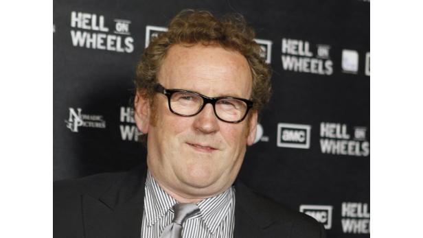 Colm Meaney vor einer Wand mit dem Logo der Serie „Hell on Wheels“.
