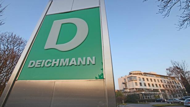 Ein Schild mit dem Deichmann-Logo vor einem mehrstöckigen Gebäude.