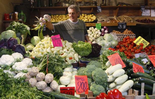 Ein Gemüsehändler präsentiert seine frische Ware auf einem Marktstand.