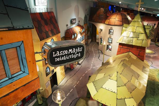 Eine stilisierte Stadtkulisse mit dem Schild „Lasse Majas Detektivbyrå“.