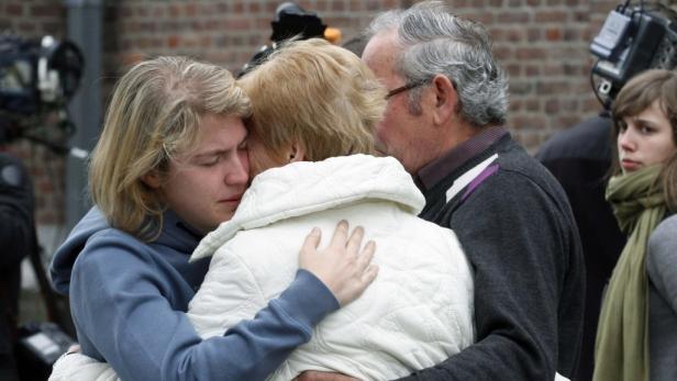 Eine junge Person umarmt weinend zwei ältere Personen.