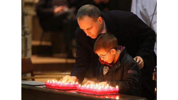 Ein Mann und ein Kind zünden Kerzen in einer Kirche an.