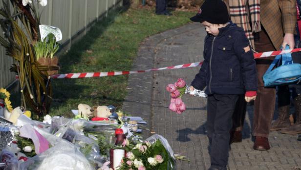 Ein Junge legt Blumen an einem improvisierten Denkmal nieder.