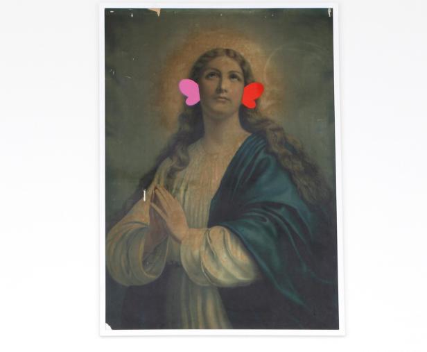 Ein Gemälde der Jungfrau Maria mit rosa und roten Papierherzen an ihren Ohren.