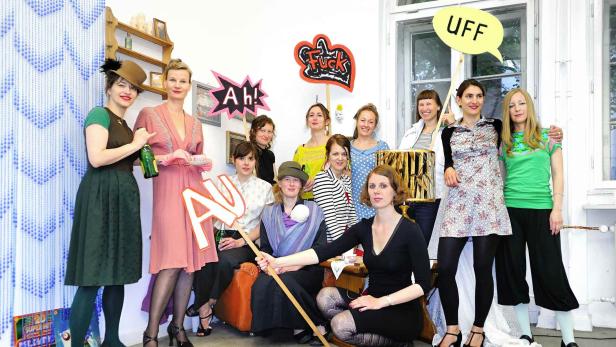 Eine Gruppe von elf Frauen posiert mit Requisiten wie Sprechblasen und Buchstaben für ein Foto.