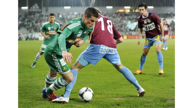 Zwei Fußballspieler kämpfen um den Ball auf dem Spielfeld.