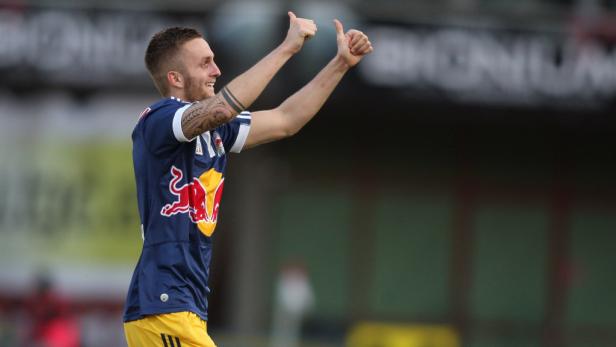 Ein Fußballspieler mit Trikot und erhobenen Daumen jubelt.