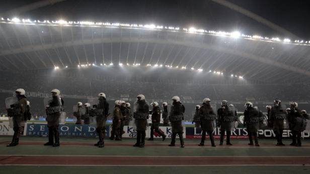Polizisten in Schutzausrüstung stehen in einem Stadion.