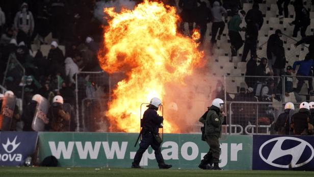 Polizisten stehen vor einem großen Feuer bei einem Fußballspiel.