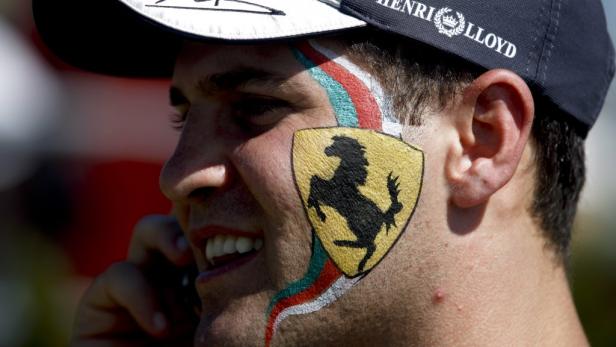 Ein Mann mit Ferrari-Logo und italienischen Farben auf dem Gesicht telefoniert.