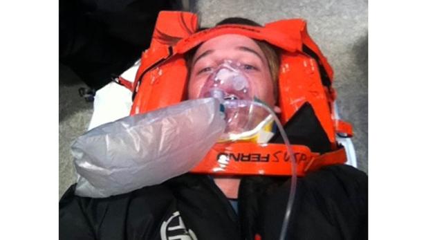 Eine Frau liegt mit Halskrause und Sauerstoffmaske auf einer Trage.