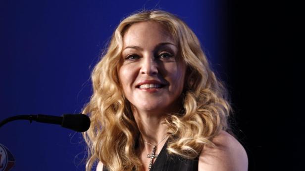 Madonna mit blonden Locken und einem Kreuz um den Hals lächelt.