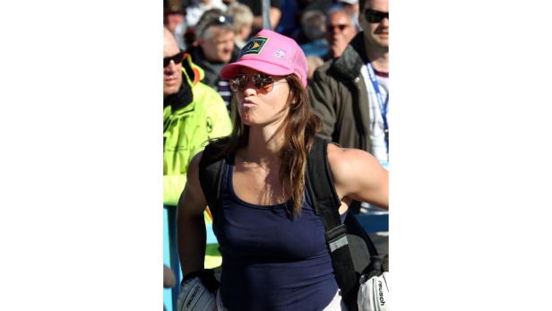 Eine Frau mit Sonnenbrille und rosa Kappe macht ein Selfie vor einer Menschenmenge.