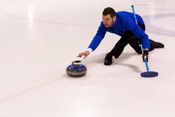 Ein Mann spielt Curling auf einer Eisbahn.