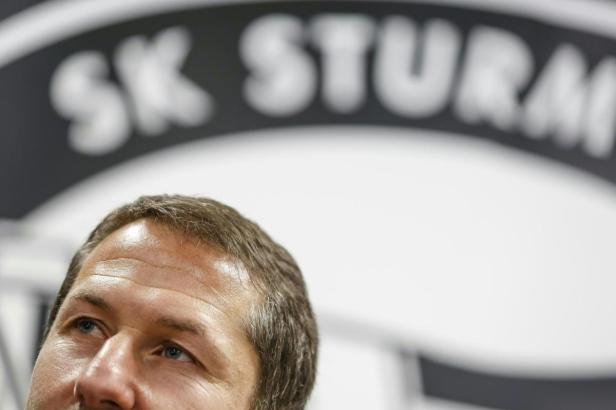 Ein Mann blickt nach oben, im Hintergrund das Logo des SK Sturm Graz.