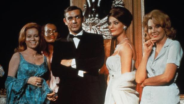 Sean Connery als James Bond, umgeben von mehreren Frauen.