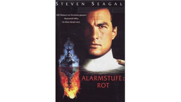 Das Filmplakat für „Alarmstufe: Rot“ mit Steven Seagal vor einem brennenden Schiff.