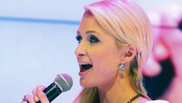 Paris Hilton singt in ein Mikrofon.