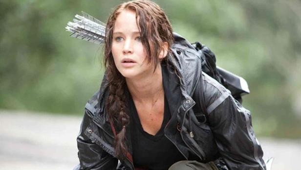 Jennifer Lawrence als Katniss Everdeen in „Die Tribute von Panem“ mit Pfeil und Bogen.