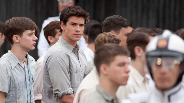 Liam Hemsworth inmitten einer Menschenmenge in grauen Uniformen.