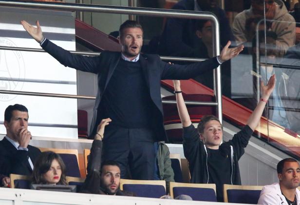David Beckham gestikuliert auf der Tribüne, während sein Sohn jubelt.