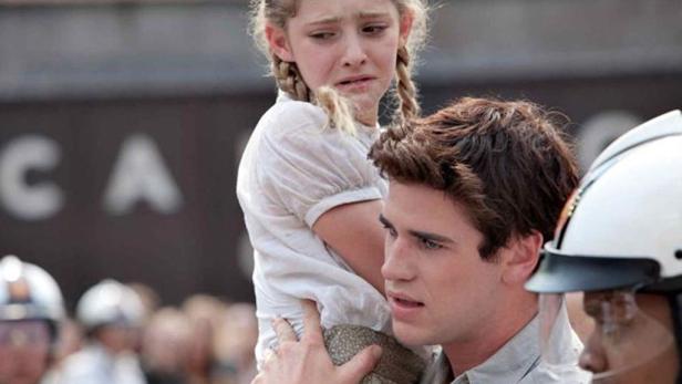 Ein Mann trägt ein weinendes Mädchen mit Zöpfen auf seinen Schultern.