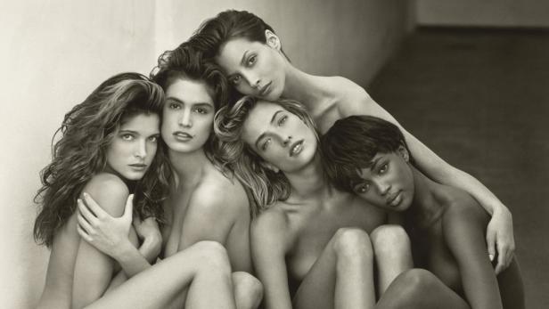 Ein Schwarzweißfoto von fünf Supermodels, darunter Cindy Crawford und Naomi Campbell, die eng beieinander sitzen.