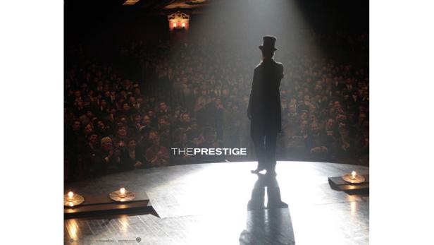 Ein Mann mit Zylinder steht auf einer Bühne vor einem Publikum im Film „The Prestige“.