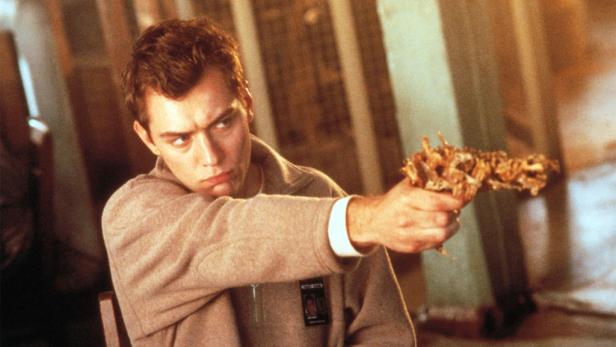 Jude Law zielt mit einer Knochenpistole in dem Film „eXistenZ“.