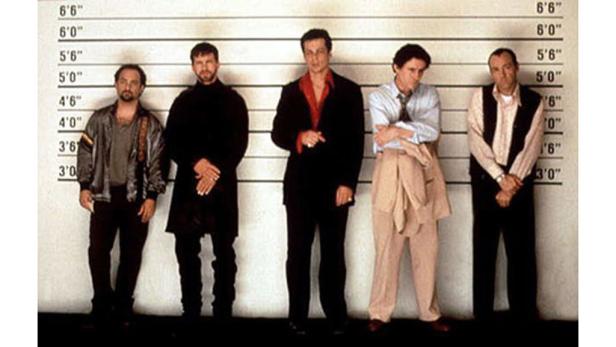 Fünf Männer stehen in einer Reihe vor einer Wand mit Größenangaben.