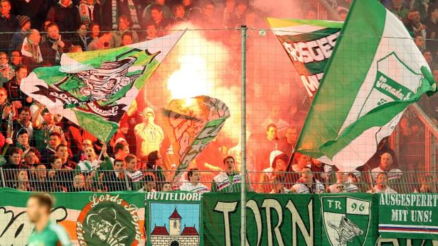 Fußballfans zünden während eines Spiels Bengalos und schwenken Fahnen.