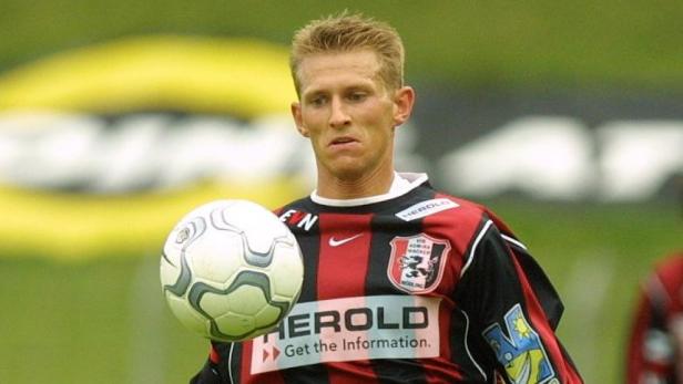 Ein Fußballspieler in rot-schwarz gestreiftem Trikot mit einem Fußball.