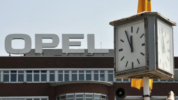 Eine Uhr vor einem Opel-Gebäude zeigt fast zwölf Uhr.