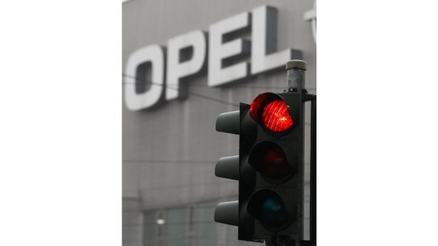 Eine rote Ampel vor einem Gebäude mit der Aufschrift „OPEL“.