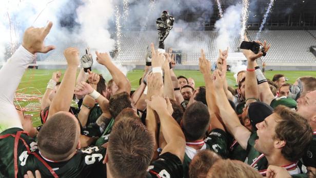 Ein American-Football-Team feiert mit dem Pokal und Konfetti den Gewinn der Meisterschaft.