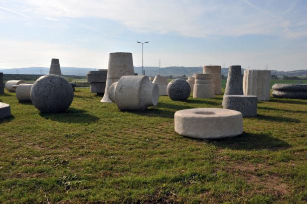 Eine Ansammlung von Betonformen unterschiedlicher Größe steht auf einer Wiese.