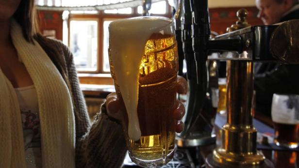 Eine Frau hält ein Glas Bier mit viel Schaum in einer Bar.